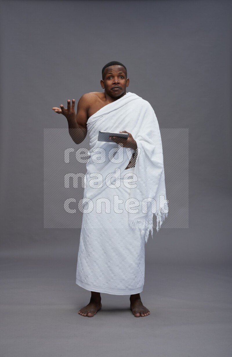 A man wearing Ehram Standing working on tablet on gray background