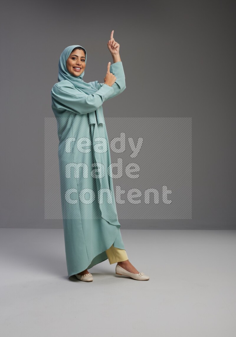 Saudi Woman wearing Abaya standing interacting with the camera on Gray background