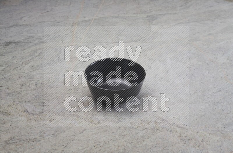 A black ceramic bowl on grey marble background