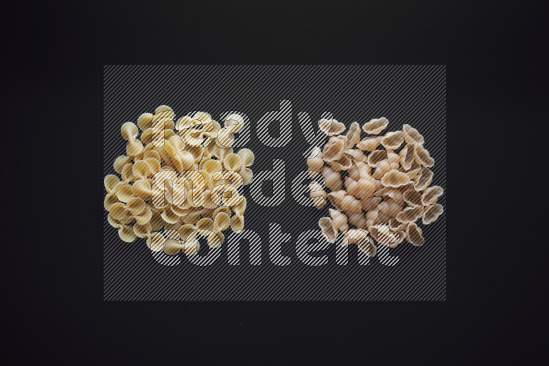 Different pasta types in bunches on black background