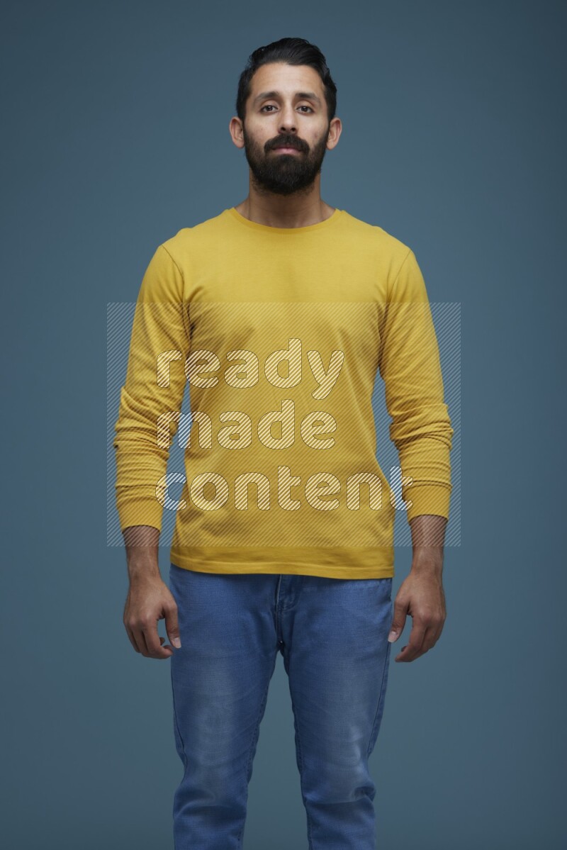 Man posing in a blue background wearing a yellow shirt