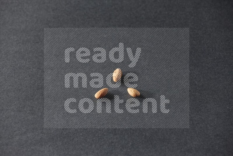 3 peeled almonds on a black background in different angles