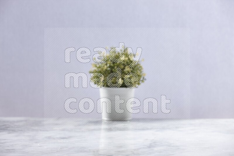 Artificial plant in white pot on grey marble background