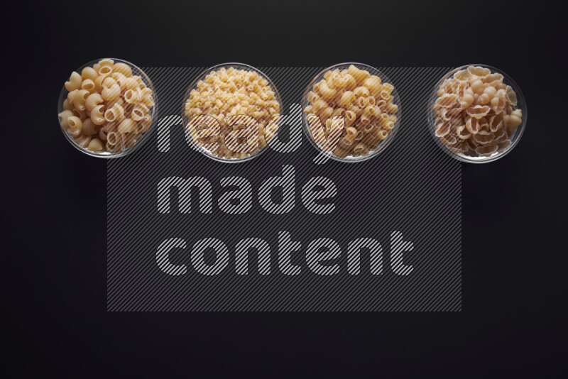 أنواع مختلفة من المعكرونة في وعاء زجاجي علي خلفية سوداء