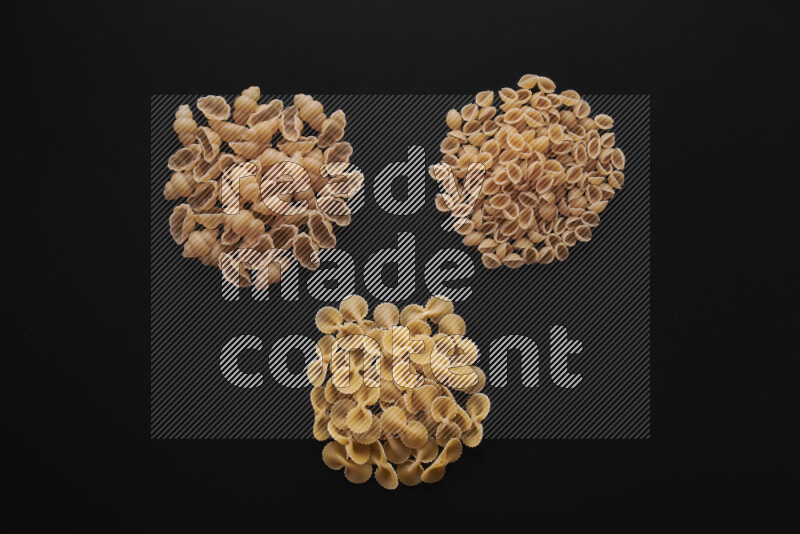 Different pasta types in bunches on black background