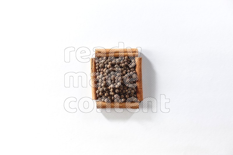 A single square of cinnamon sticks full of allspice on white flooring