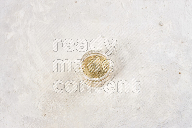 A glass jar full of ground ginger powder on white background