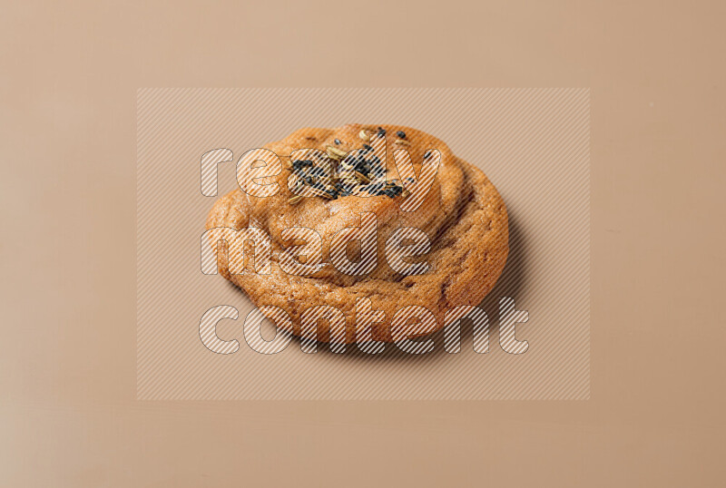 a whole Hasawi cookie with grains on a brown background