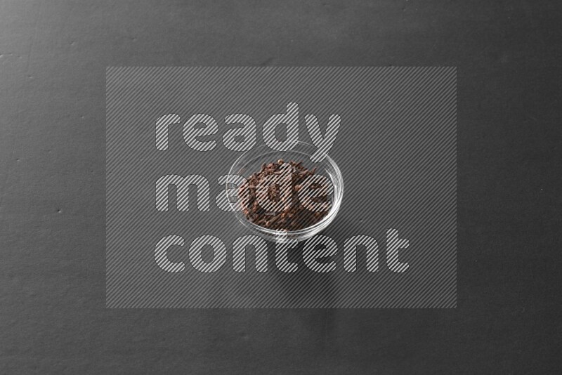 A glass bowl full of cloves on black flooring