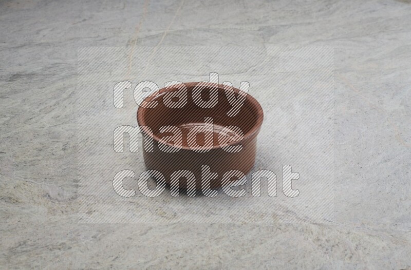 A brown pottery bowl on grey marble background