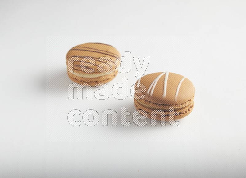 45º Shot of of two assorted Brown Irish Cream, and light brown  Almond Cream macarons on white background