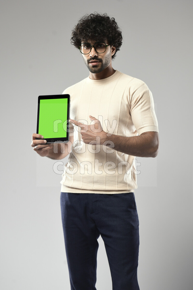 A man wearing casual standing and showing a tablet screen on white background