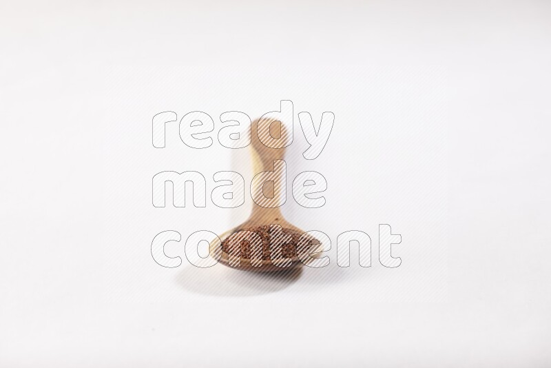 ملعقة خشبية كبيرة ممتلئة ببذور حب الرشاد علي خلفية بيضاء