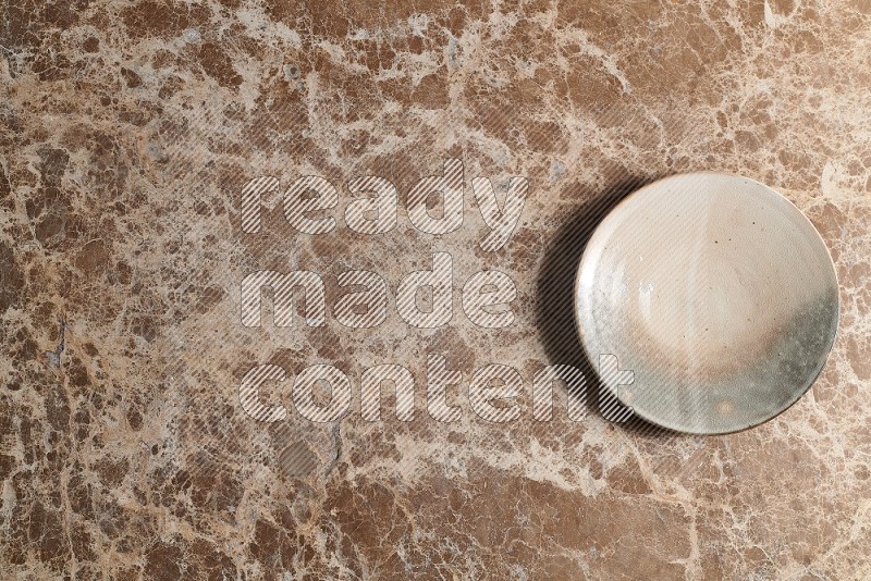 Top View Shot Of A Multicolored Pottery plate On beige Marble Flooring