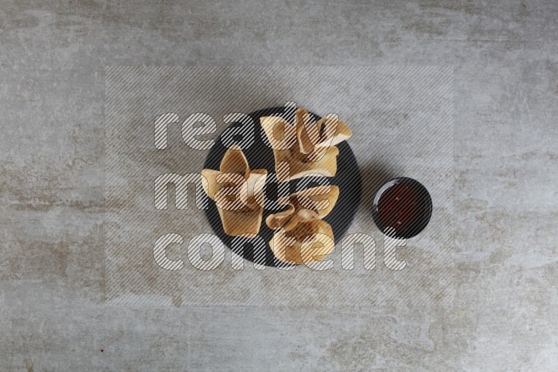 wonton cups with soy sauce ramkin on circle slate on grey textured counter top
