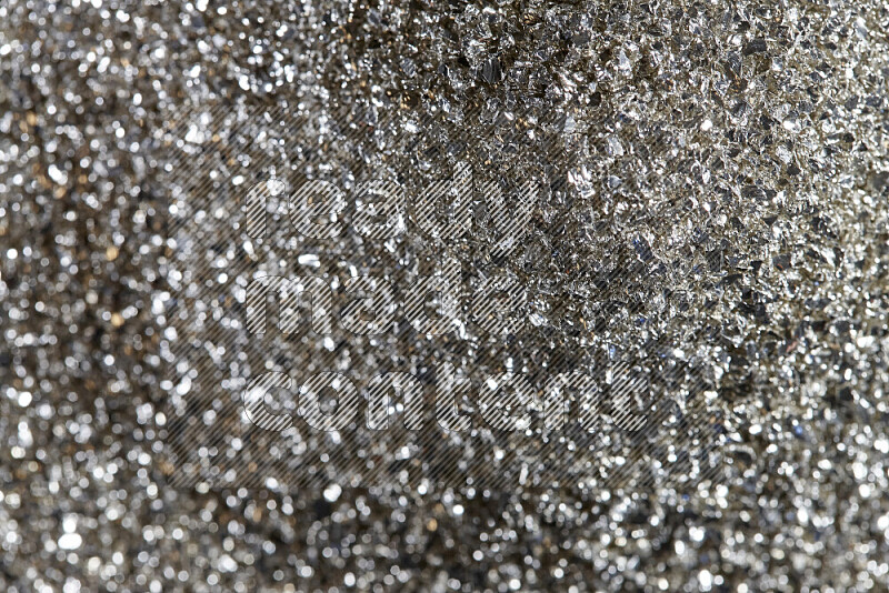 Silver shimmering fragments of glass scattered on a black background