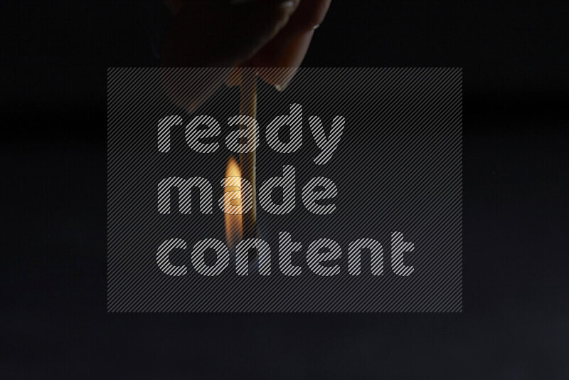 A burning matchstick isolated on dark backdrop