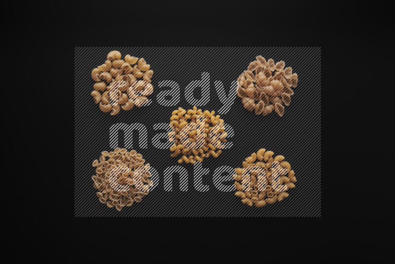 Different pasta types in bunches on black background