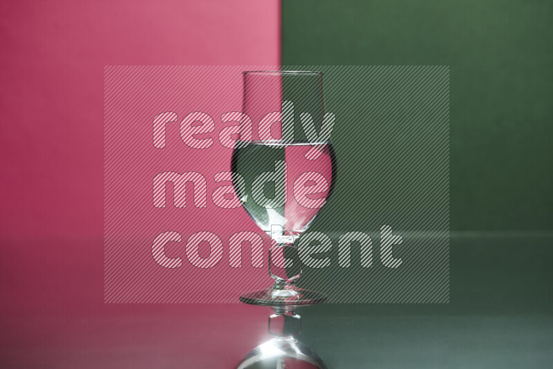 The image features a clear glassware filled with water, set against pink and dark green background