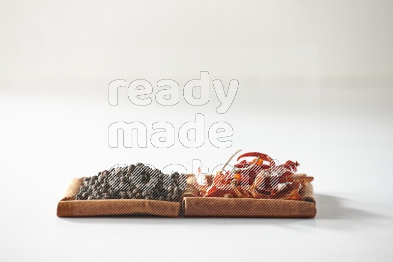 2 squares of cinnamon sticks full of red dried chilis and black pepper on white flooring