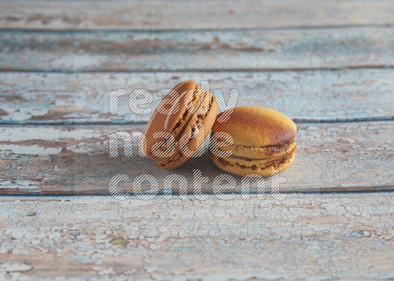45º Shot of of two assorted Brown Irish Cream, and Yellow Crème Brulée macarons on light blue background