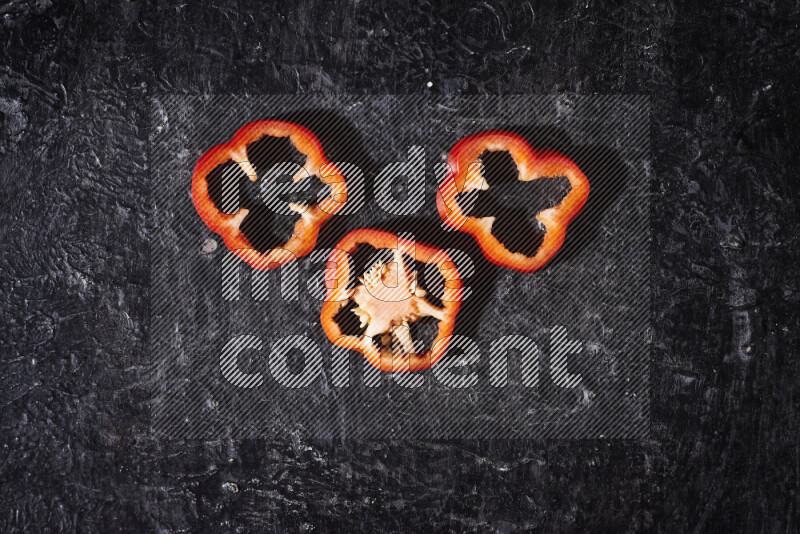 Red bell pepper slices on black background
