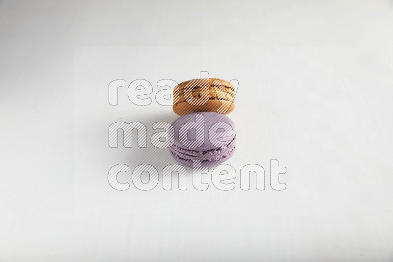 45º Shot of of two assorted Brown Irish Cream, and Purple Blueberry macarons on white background