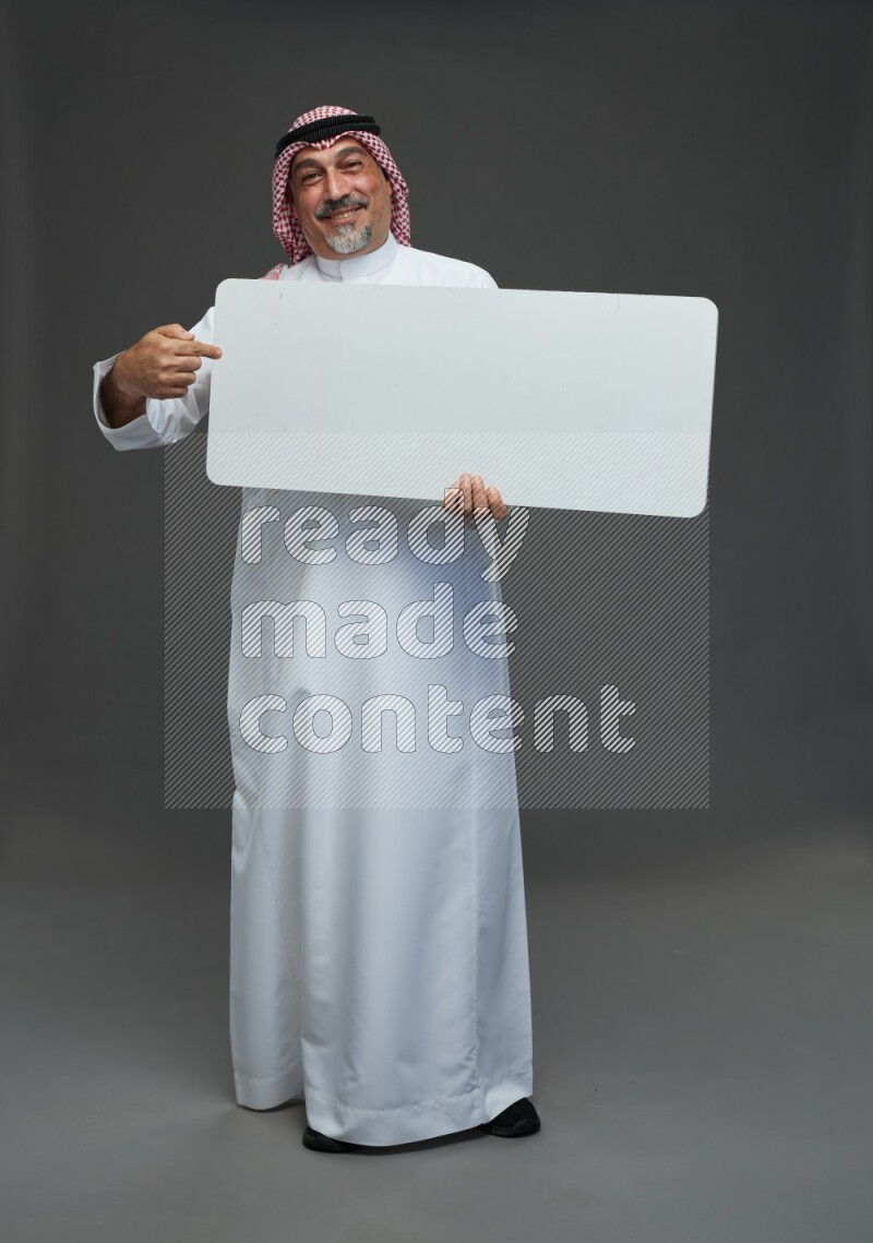 Saudi man with shomag Standing holding social media sing on gray background