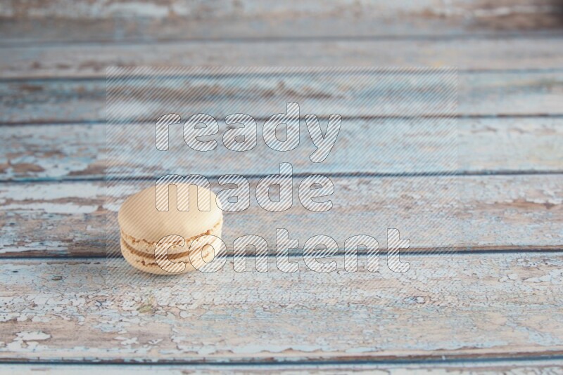 45º Shot of White Caramel fleur de sel macaron on light blue wooden background