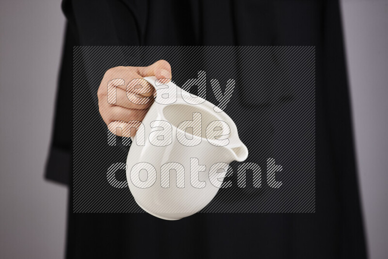 A woman in black abaya holding different pottery essentials in different positions