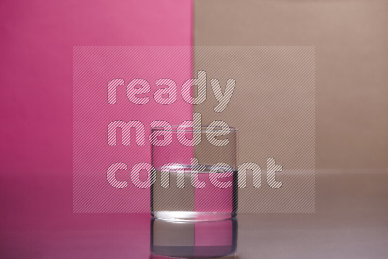 The image features a clear glassware filled with water, set against pink and beige background