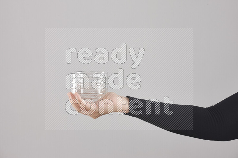 A woman in black abaya holding different glassware in different positions