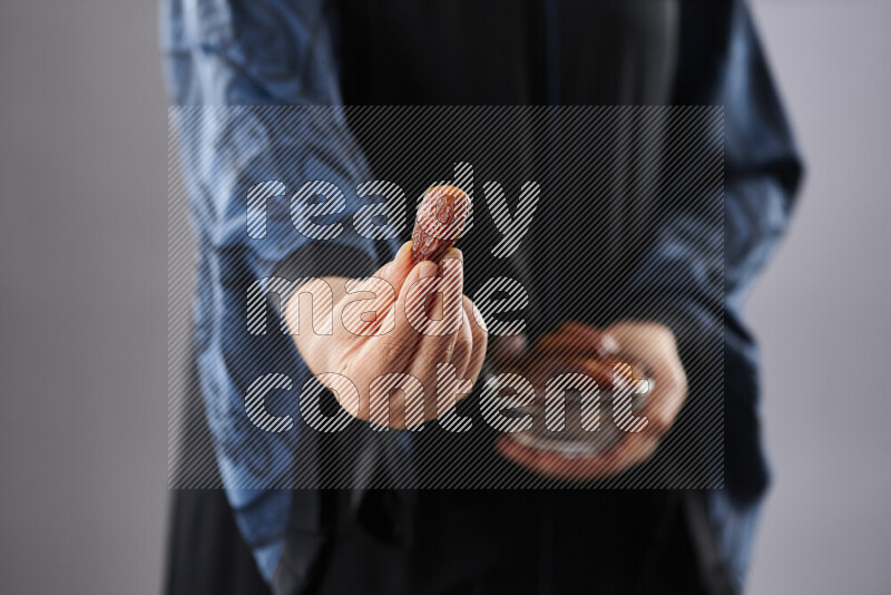 Woman in abaya holding dates in different positions
