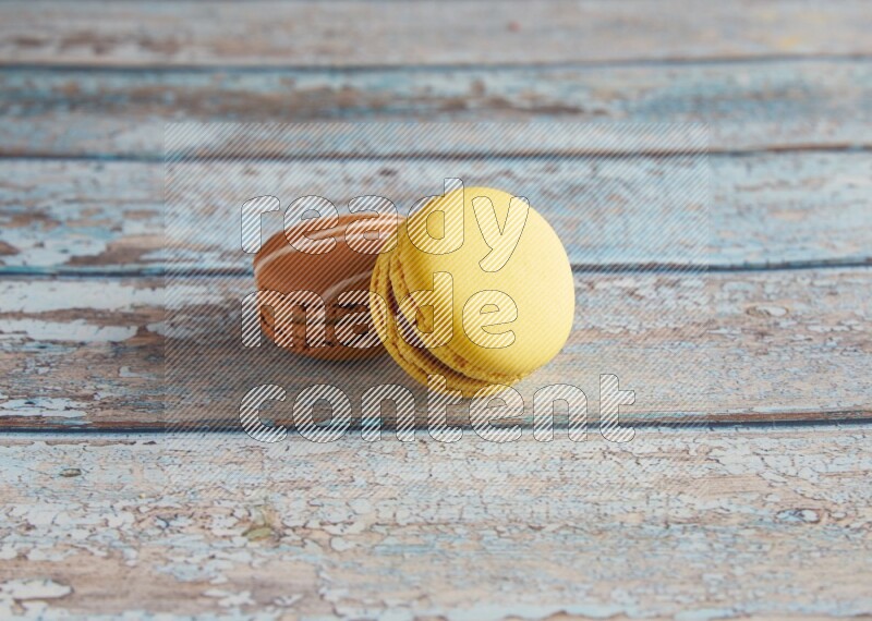 45º Shot of of two assorted Brown Irish Cream, and Yellow Lemon macarons on light blue background