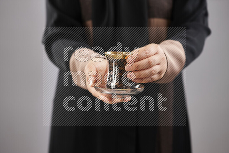 Woman in abaya holding different kinds of coffee beans in different positions
