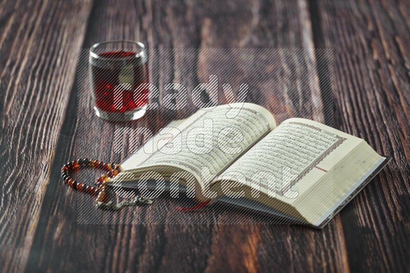 Quran with dates, prayer beads and different drinks all placed on wooden background