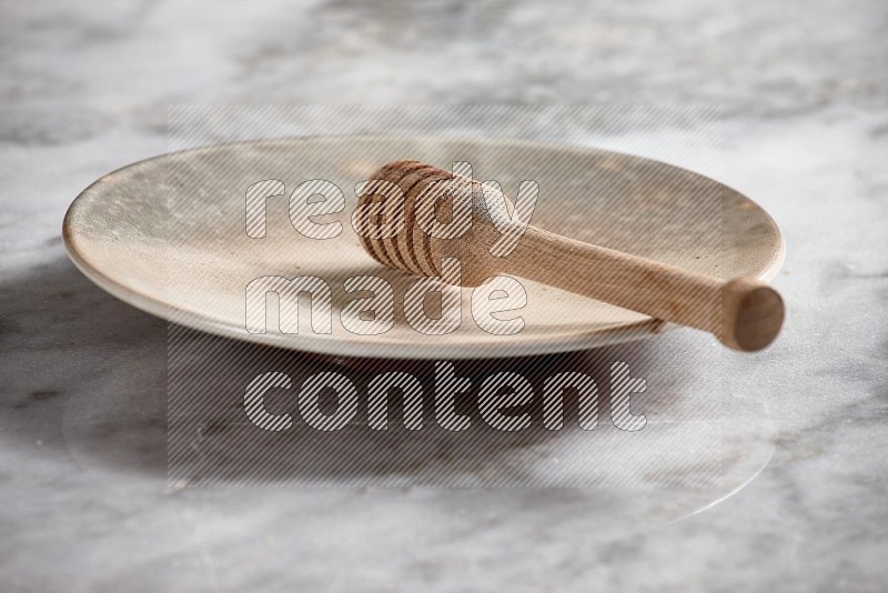 Multicolored Pottery Plate with wooden honey handle in it, on grey marble flooring, 15 degree angle