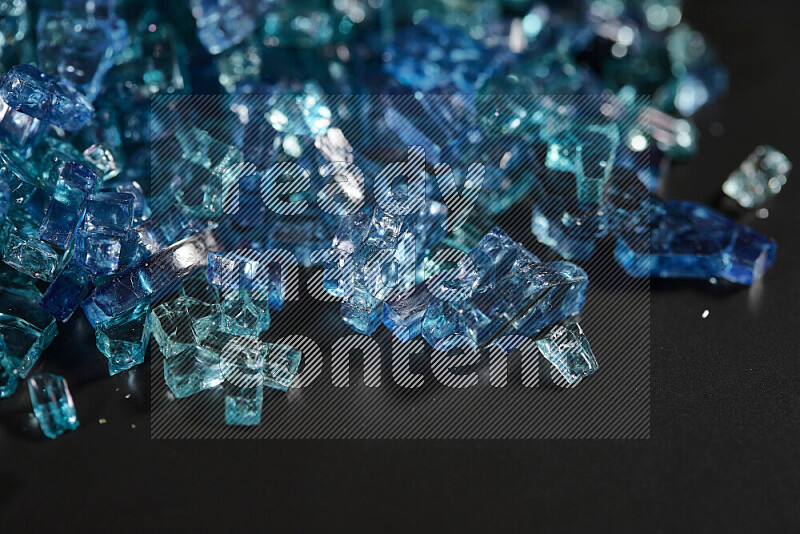 Transparent blue fragments of glass scattered on a black background