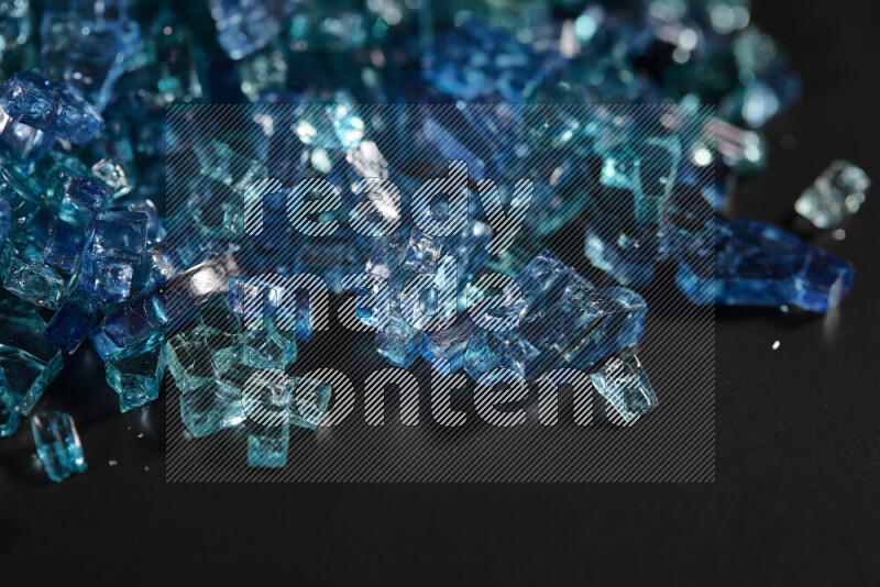 Transparent blue fragments of glass scattered on a black background