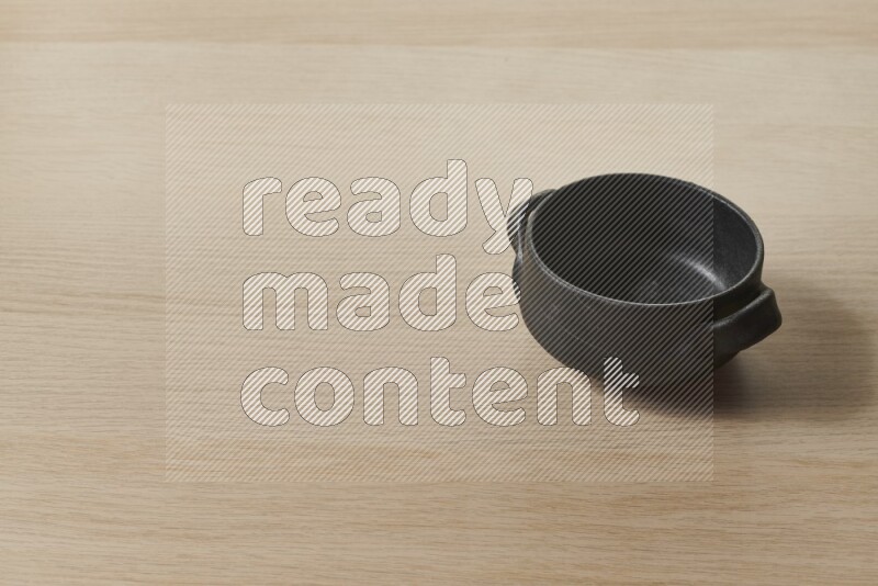 A black pottery bowl on light wooden background