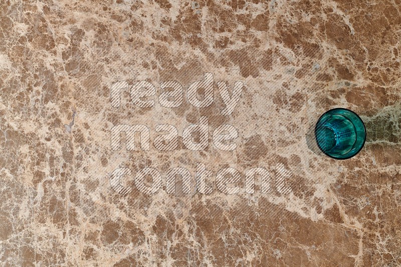 Top View Shot Of A Turquoise Glass On beige Marble Flooring
