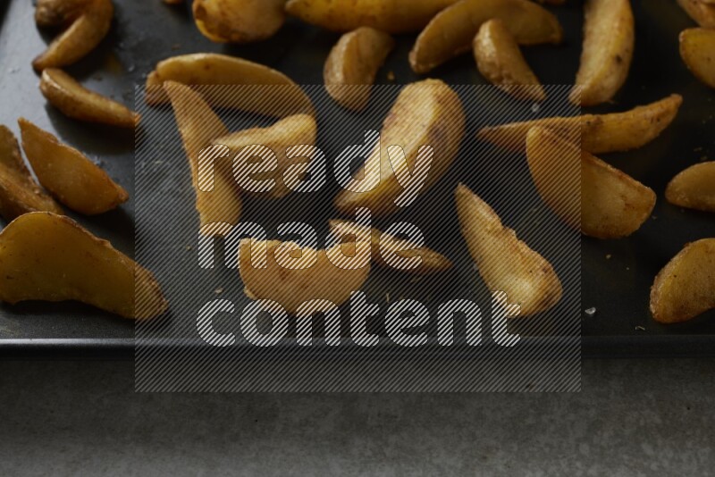 wedges potato in a black stainless steel rectangle tray on grey textured counter top