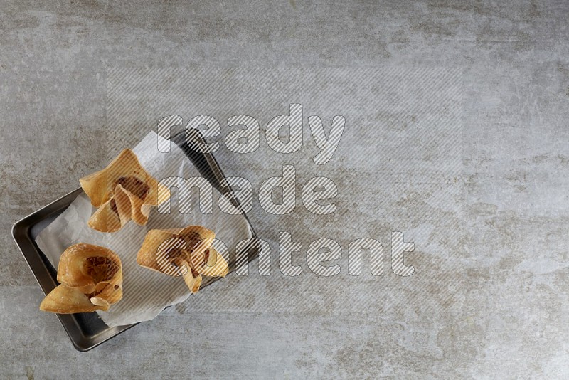 wonton cups on parchment paper in stainless tray on grey textured counter top