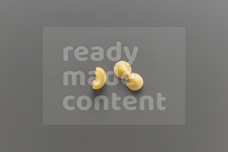 Elbow pasta with other types of pasta on grey background
