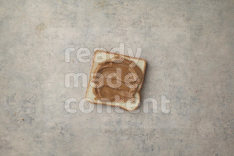 Creamy peanut butter on a white toast on a light blue textured background