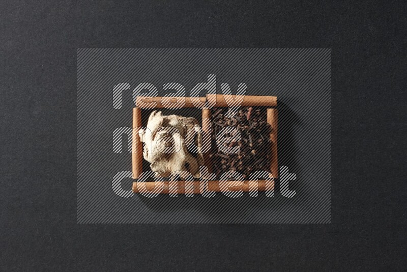 2 squares of cinnamon sticks full of cloves and dried ginger on black flooring