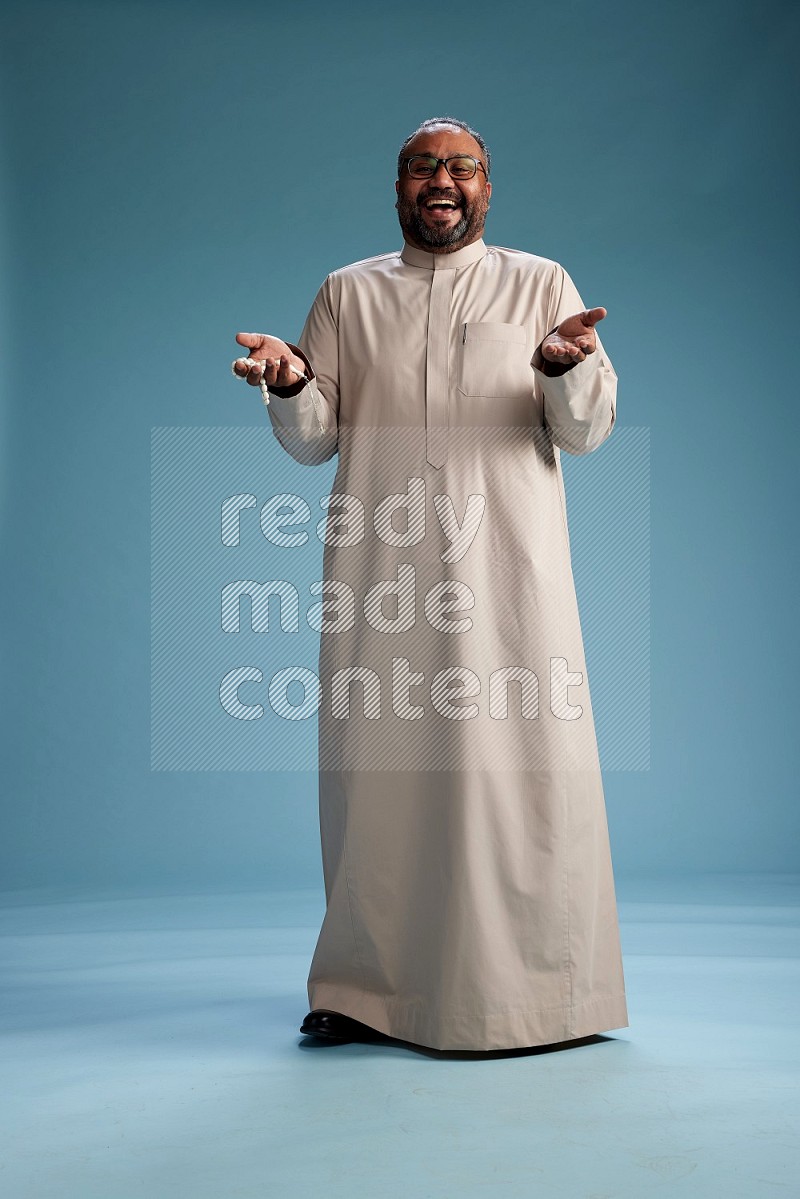 Saudi Man without shimag Standing Interacting with the camera on blue background