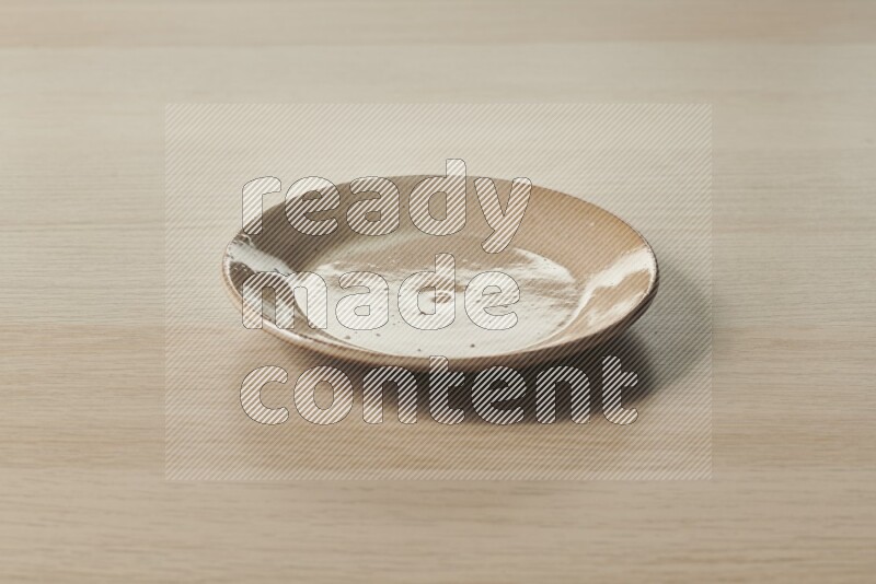 A beige pottery plate on light wooden background