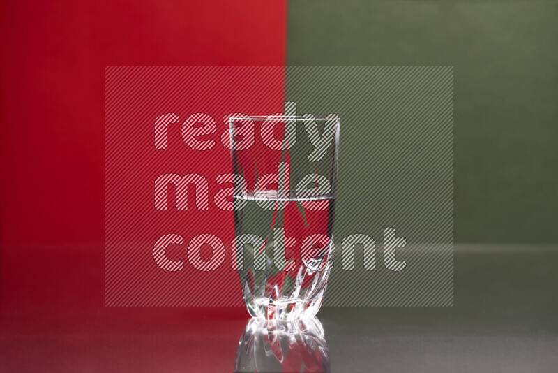 The image features a clear glassware filled with water, set against red and dark green background