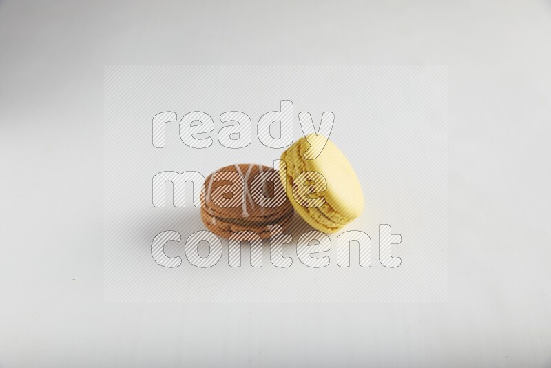 45º Shot of of two assorted Brown Irish Cream, and Yellow Lemon macarons on white background
